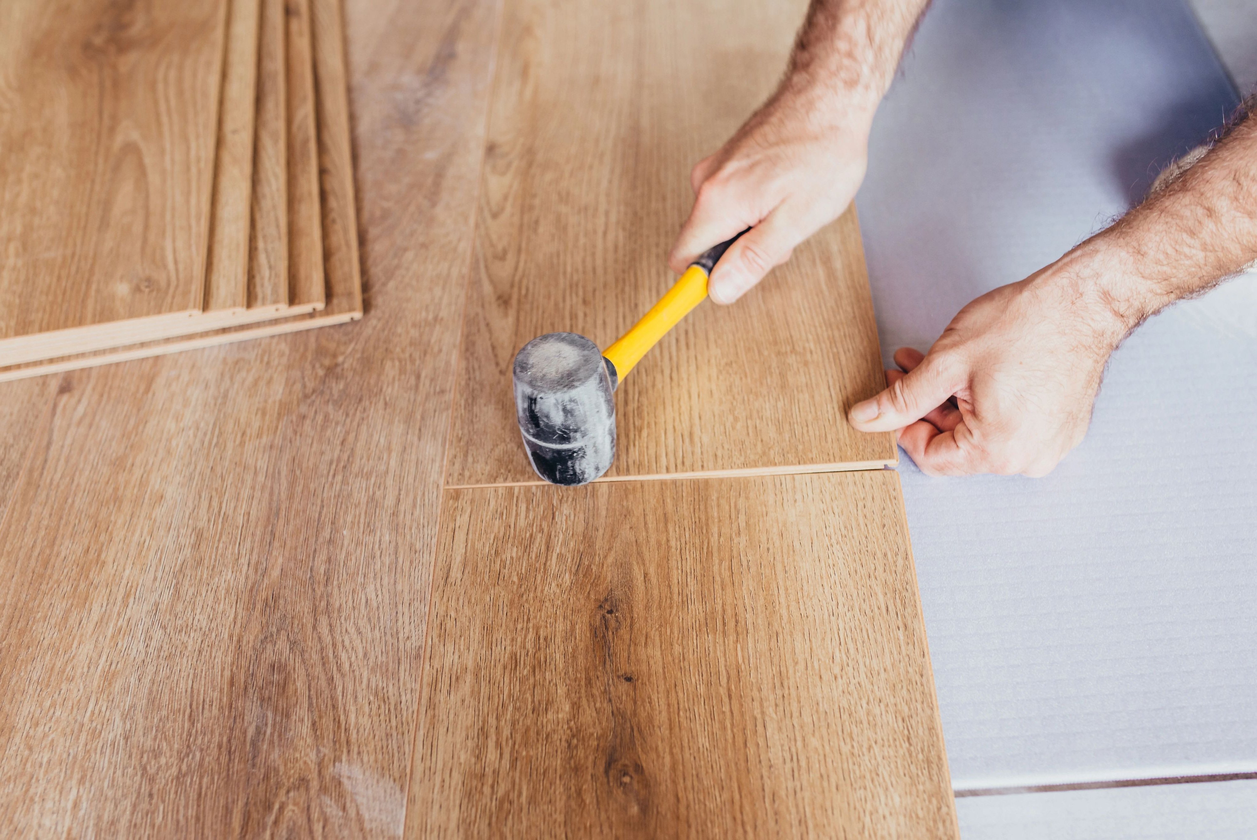 Person installing engineered hardwood flooring from Scott's Flooring in Barrie, ON